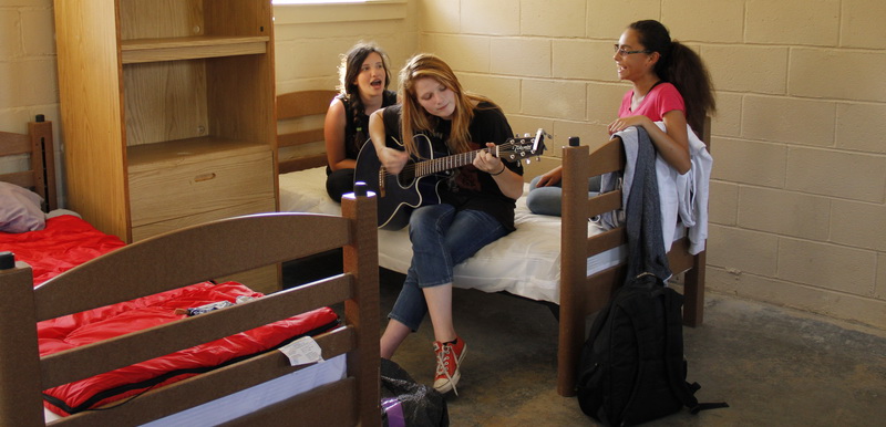 lady playing guitar and two girls singing inside the youth group camping bedroom