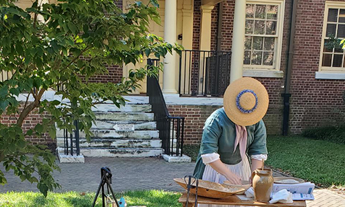 A woman in front of John Bell House at First State Heritage State Park