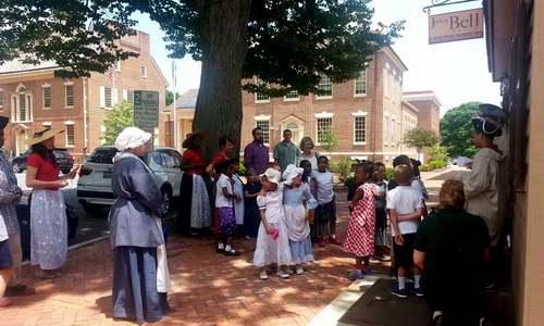 colonial dressed tour guides and group on sidewalk in front of John Bell house